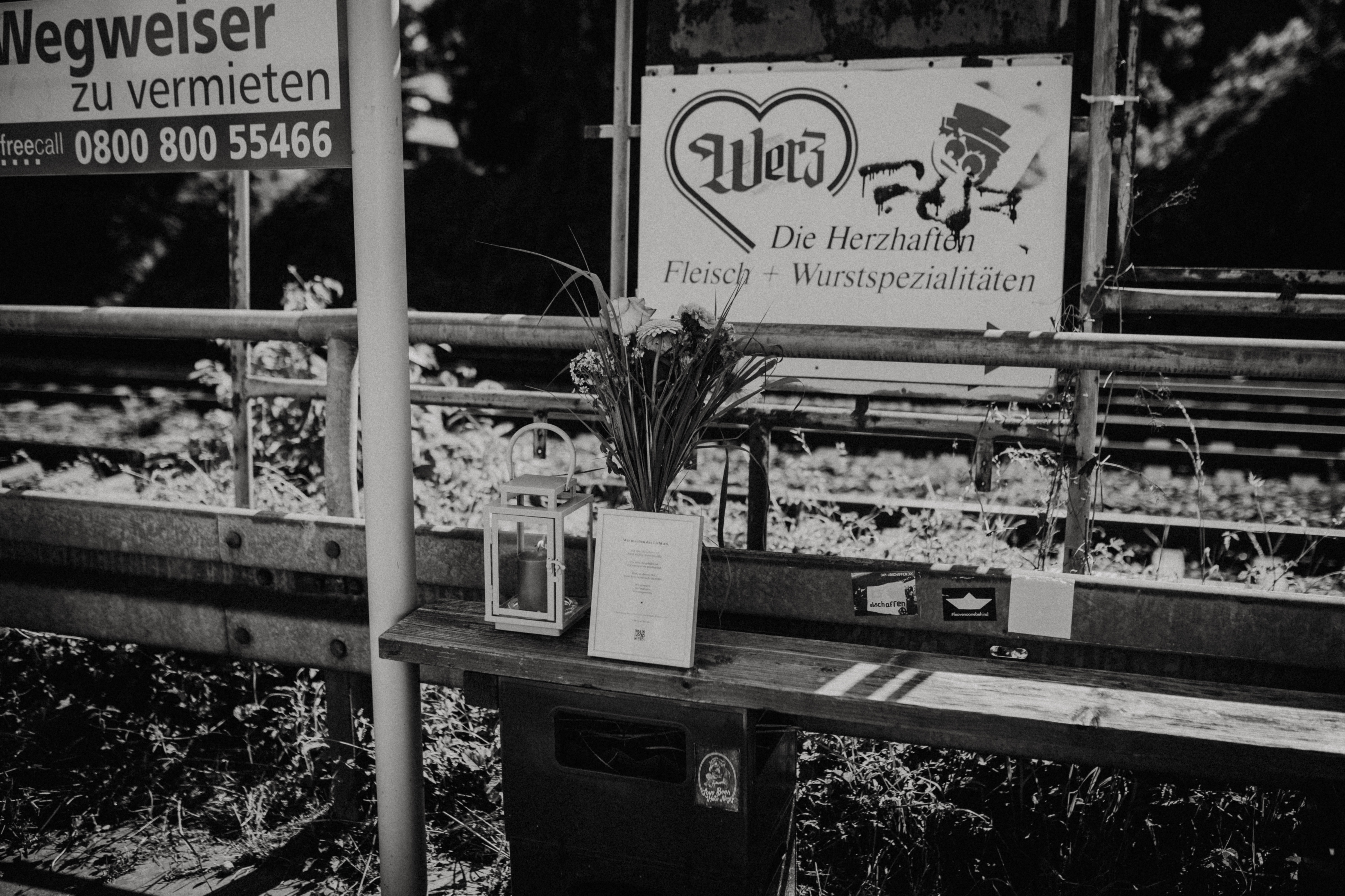 Mahnmal mit Kerze und Blumen